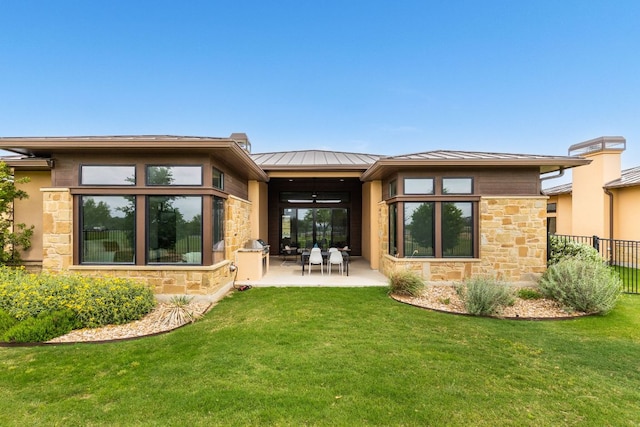 2317 Kahala Sunset Dr, Spicewood, TX 78669 - rear view of property featuring a patio area, a yard, stone siding, and a standing seam roof