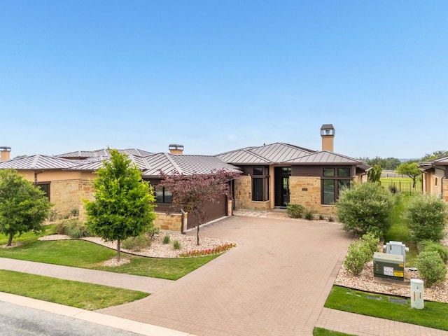 2317 Kahala Sunset Dr, Spicewood, TX 78669 - prairie-style house with a standing seam roof, a chimney, decorative driveway, and metal roof