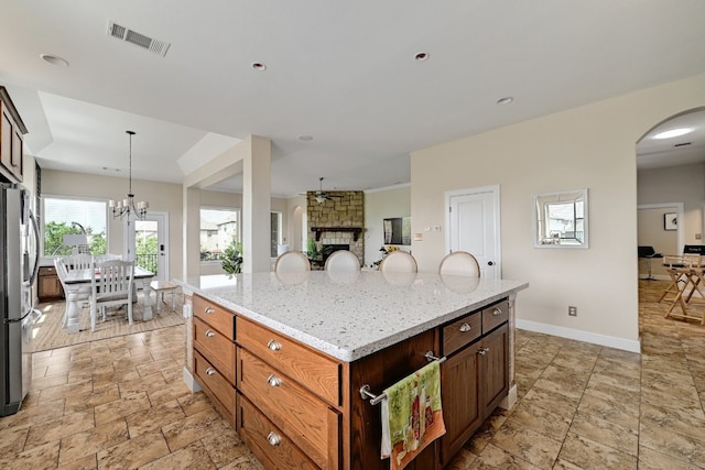 kitchen featuring visible vents, arched walkways, light stone countertops, baseboards, and freestanding refrigerator