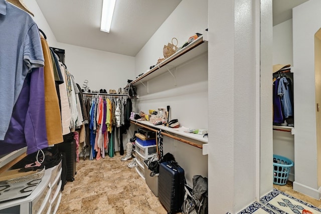 walk in closet featuring stone finish flooring