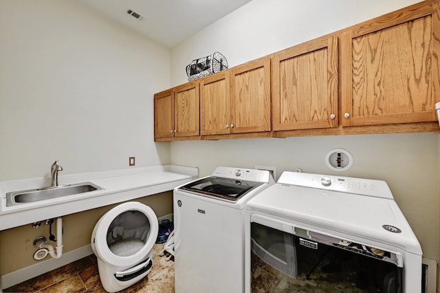 washroom featuring cabinet space, a sink, stone finish flooring, visible vents, and washing machine and dryer
