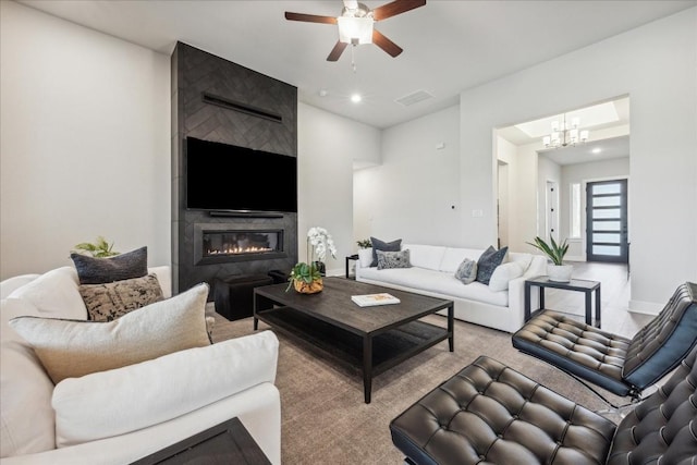 living area with carpet floors, ceiling fan with notable chandelier, visible vents, and a large fireplace