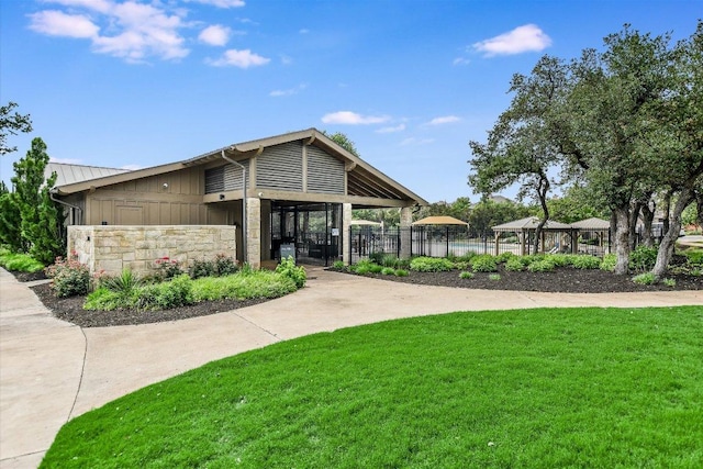 view of community with a gazebo, a lawn, and fence