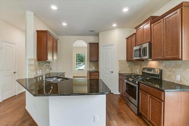 kitchen with visible vents, appliances with stainless steel finishes, arched walkways, a sink, and dark wood-style floors