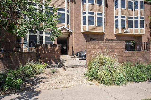 view of side of home with brick siding and fence