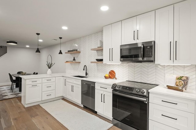 kitchen featuring open shelves, appliances with stainless steel finishes, a sink, light countertops, and wood finished floors
