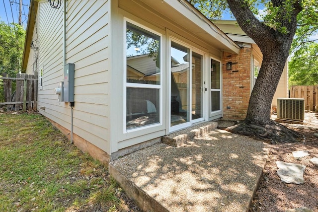 view of side of property featuring brick siding, fence, and central AC unit