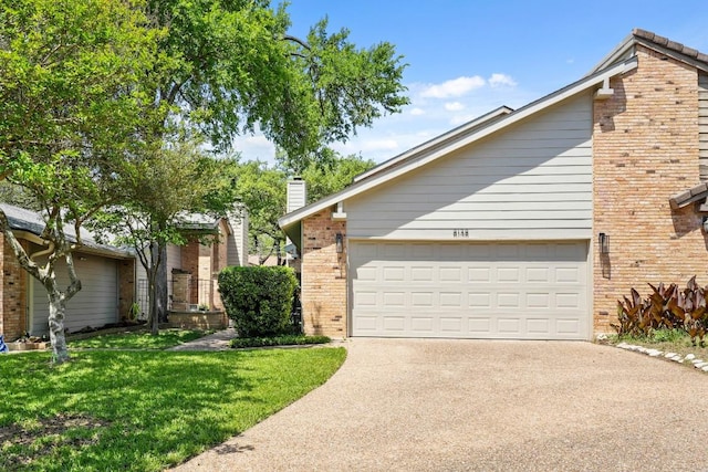 view of front of house featuring a front lawn, brick siding, a garage, a chimney, and concrete driveway