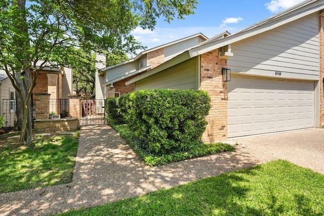 view of front of home featuring driveway, a gate, brick siding, fence, and an attached garage