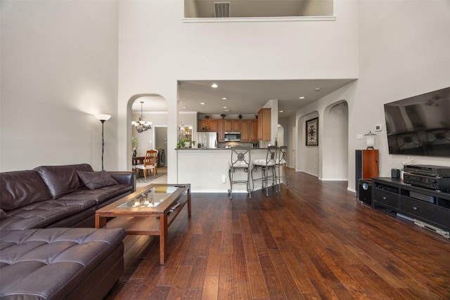 living area with arched walkways, a high ceiling, and a notable chandelier