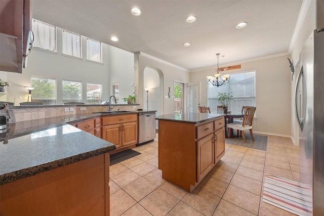 kitchen with a notable chandelier, appliances with stainless steel finishes, a sink, arched walkways, and a healthy amount of sunlight