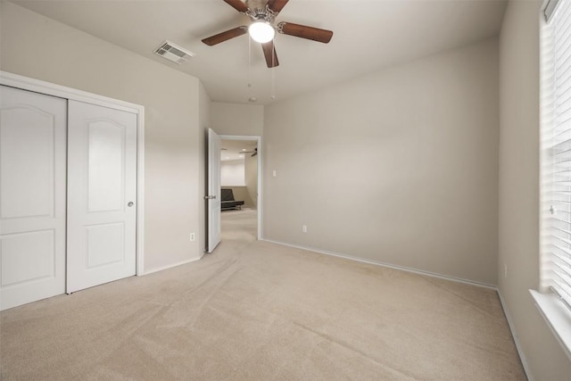 unfurnished bedroom with baseboards, visible vents, light carpet, and a closet
