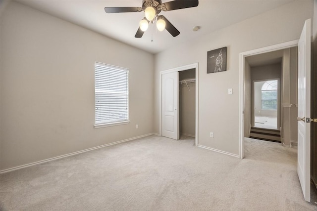 unfurnished bedroom featuring a ceiling fan, baseboards, light carpet, and a closet