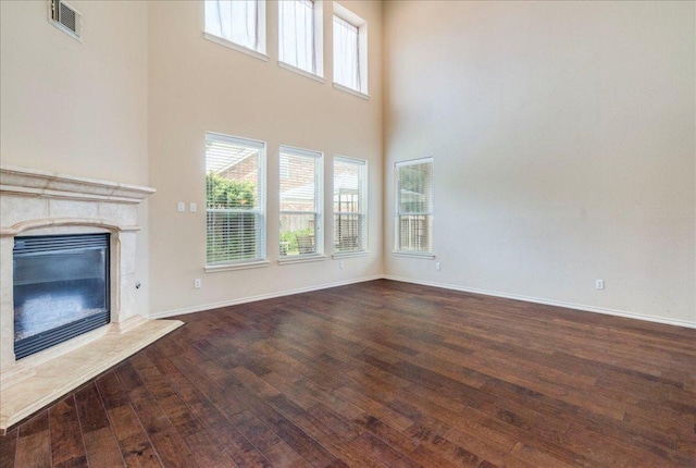 3012 Centennial Olympic Park, Austin, TX 78732 - unfurnished living room with wood-type flooring, a fireplace, a towering ceiling, and baseboards