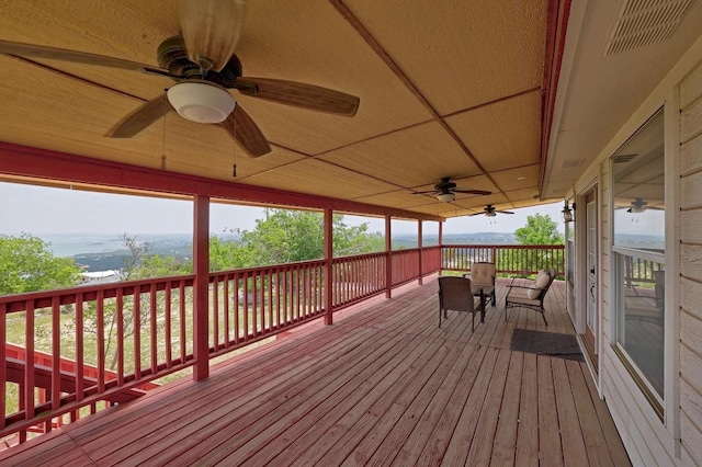 wooden terrace with a ceiling fan and visible vents