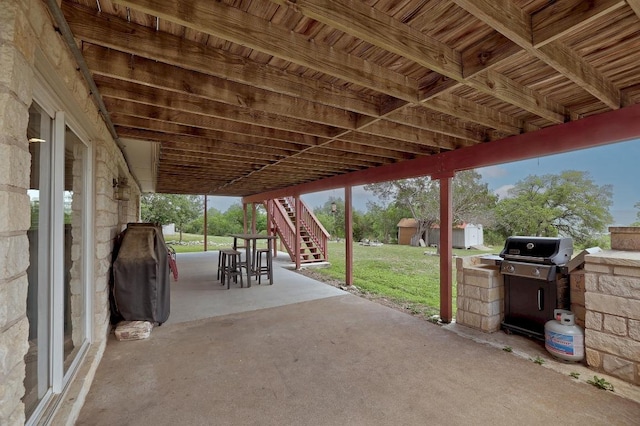 view of patio / terrace with a storage shed, an outbuilding, stairs, and area for grilling