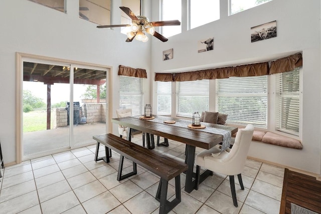 dining space featuring ceiling fan, a high ceiling, light tile patterned flooring, and a wealth of natural light