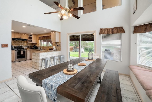 dining area with a ceiling fan, light tile patterned floors, a high ceiling, and a wealth of natural light