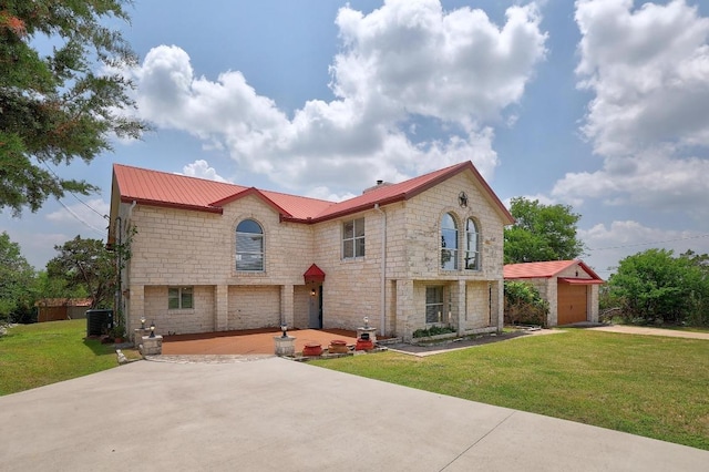 view of front of house featuring an outdoor structure, a front yard, stone siding, driveway, and a detached garage