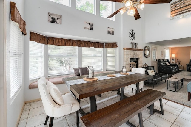 dining space featuring light tile patterned floors, plenty of natural light, ceiling fan, and a towering ceiling