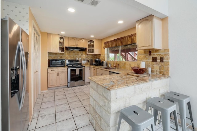 kitchen featuring exhaust hood, appliances with stainless steel finishes, a sink, a peninsula, and glass insert cabinets