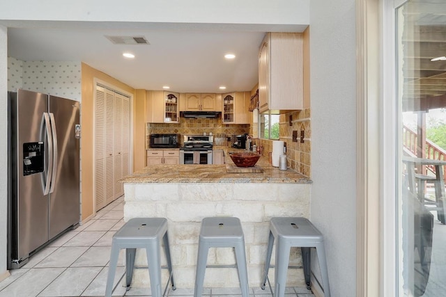 kitchen featuring visible vents, appliances with stainless steel finishes, a peninsula, glass insert cabinets, and under cabinet range hood
