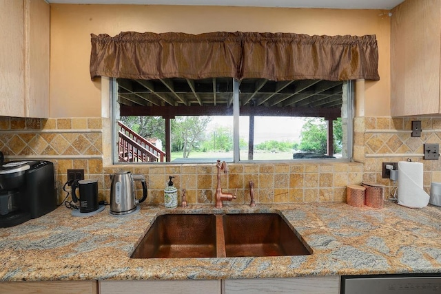 kitchen with a sink, stainless steel dishwasher, light stone countertops, and backsplash