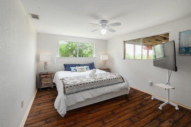 bedroom with baseboards, visible vents, a textured wall, and wood finished floors