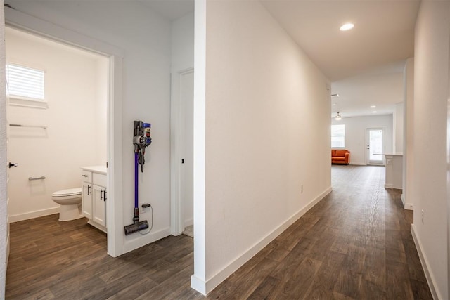 hallway featuring dark wood-type flooring, recessed lighting, and baseboards