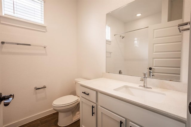 bathroom with a shower, wood finished floors, vanity, baseboards, and toilet