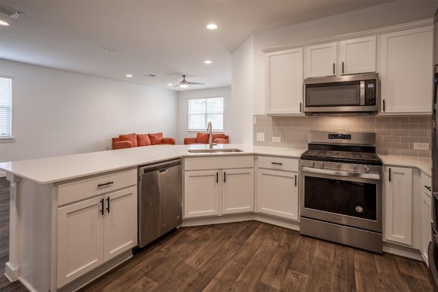 kitchen featuring a sink, appliances with stainless steel finishes, a peninsula, and light countertops