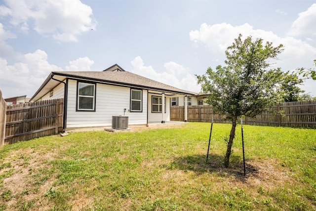 rear view of house featuring central air condition unit, a yard, and a fenced backyard