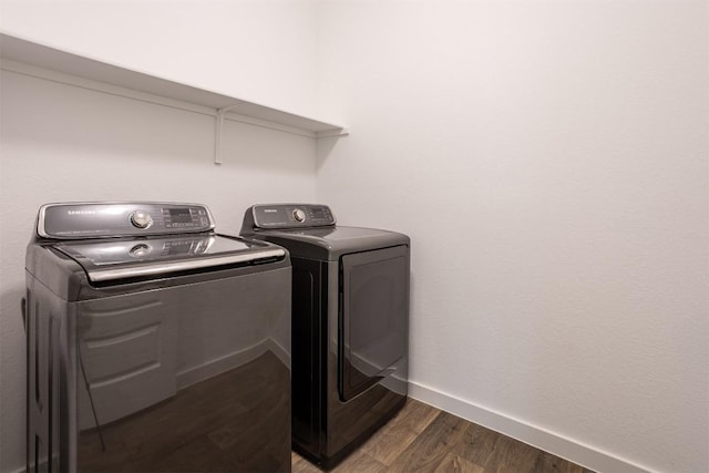 laundry room with baseboards, laundry area, washing machine and dryer, and wood finished floors