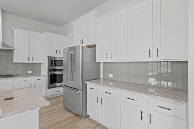 kitchen featuring appliances with stainless steel finishes, decorative backsplash, light wood-style flooring, and white cabinetry