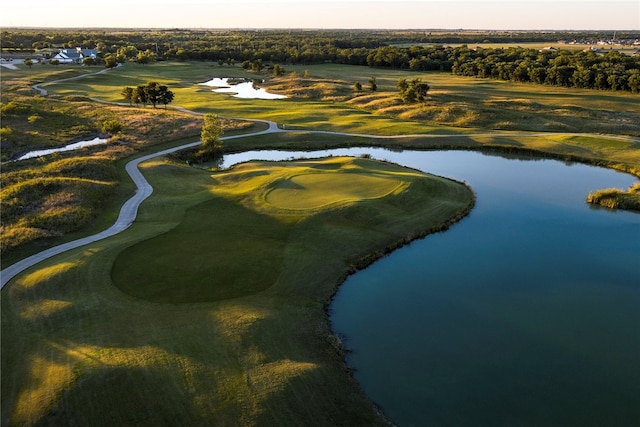aerial view at dusk featuring a water view and golf course view