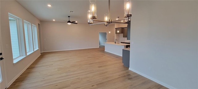 118 Freeman Day Dr, Bastrop, TX 78602 - unfurnished living room with a sink, ceiling fan, light wood-style floors, a chandelier, and baseboards
