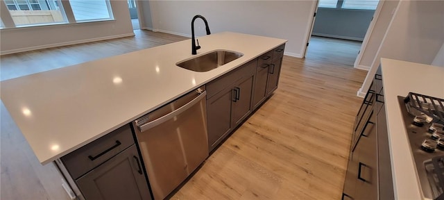 118 Freeman Day Dr, Bastrop, TX 78602 - kitchen featuring stainless steel dishwasher, a sink, light wood-style flooring, light countertops, and baseboards