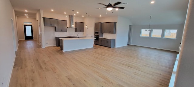 118 Freeman Day Dr, Bastrop, TX 78602 - kitchen with open floor plan, wall chimney range hood, a kitchen island with sink, backsplash, and light wood-style flooring