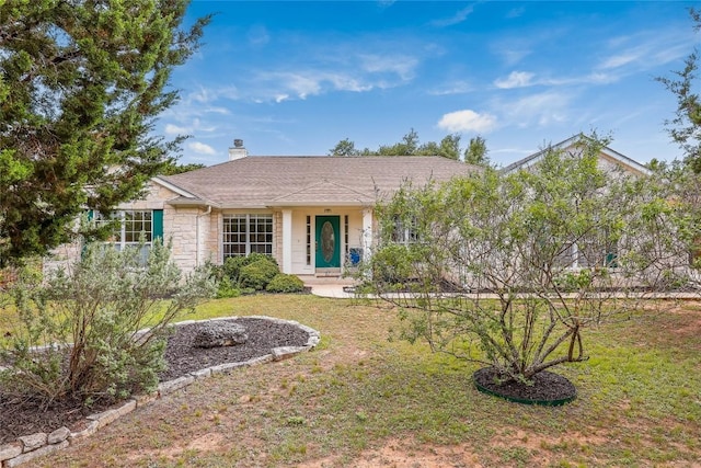 ranch-style home with a front lawn, stone siding, and a chimney