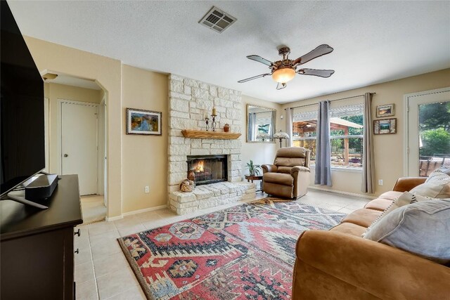 20603 Camel Back St, Lago Vista, TX 78645 - living room featuring light tile patterned floors, a ceiling fan, a fireplace, baseboards, and a textured ceiling