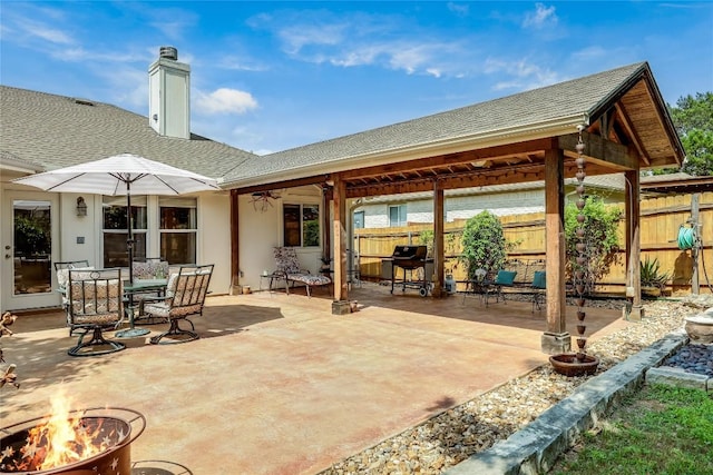 view of patio featuring ceiling fan, fence, a fire pit, and outdoor dining area