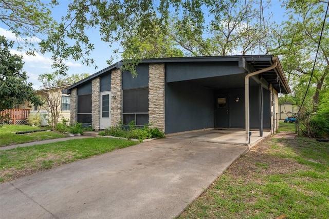 view of front of house featuring a front yard, stone siding, and concrete driveway