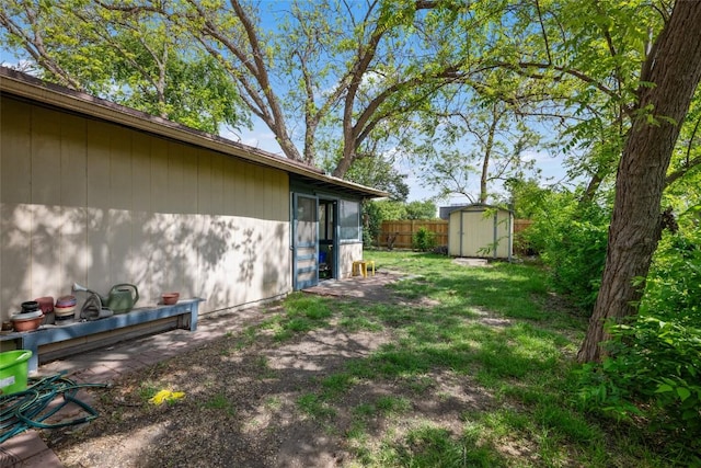 view of yard featuring an outdoor structure, fence, and a storage shed