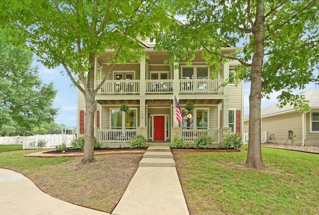 greek revival house with a porch, a front lawn, fence, and a balcony