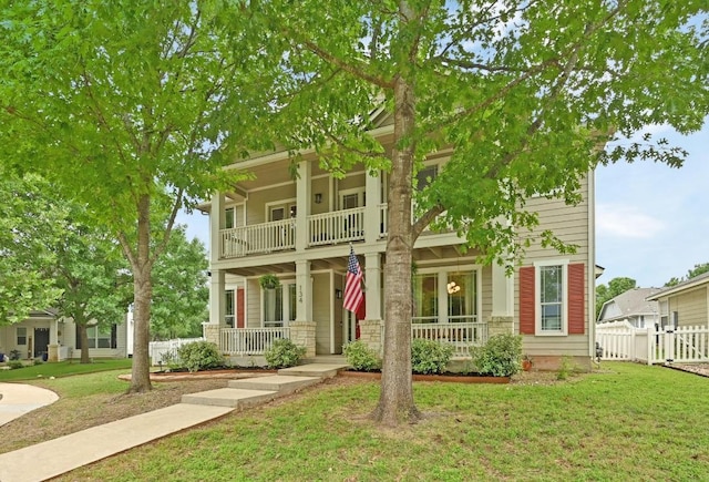 view of front facade with covered porch, fence, a balcony, and a front lawn