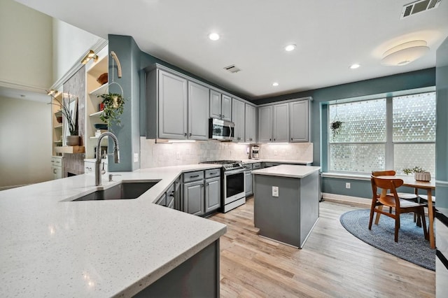 kitchen with visible vents, a sink, backsplash, gray cabinetry, and stainless steel appliances