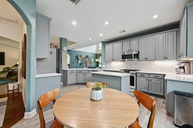 kitchen with stainless steel appliances, visible vents, gray cabinets, and light wood-style flooring