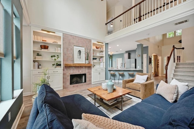 living area featuring a fireplace, arched walkways, stairs, a towering ceiling, and visible vents