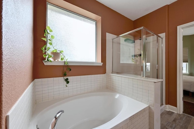 full bath featuring plenty of natural light, a shower stall, and a garden tub