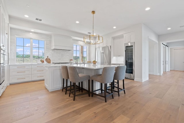 6013 Silver Luna Way, Austin, TX 78738 - kitchen with appliances with stainless steel finishes, premium range hood, healthy amount of natural light, a center island with sink, and recessed lighting